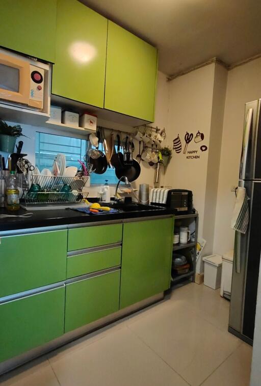 Modern kitchen with green cabinets and various appliances