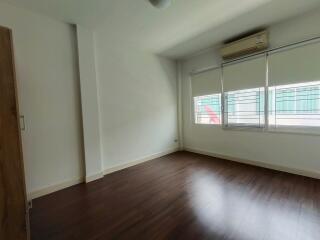 Spacious empty bedroom with wooden floor and large windows