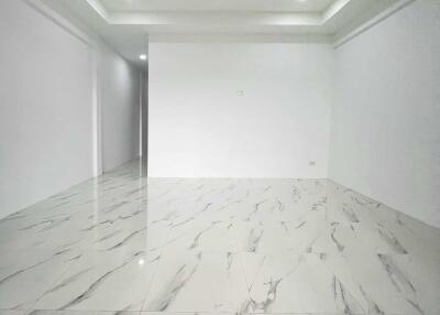 Spacious, unfurnished main living area with marble floor tiling and recessed lighting