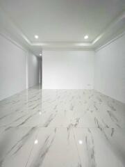 Spacious, unfurnished main living area with marble floor tiling and recessed lighting