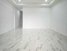 Spacious, unfurnished main living area with marble floor tiling and recessed lighting