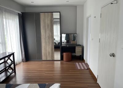 Modern bedroom with wooden flooring, wardrobe, and dressing table
