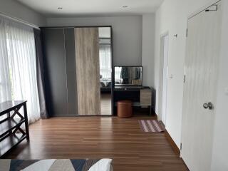 Modern bedroom with wooden flooring, wardrobe, and dressing table