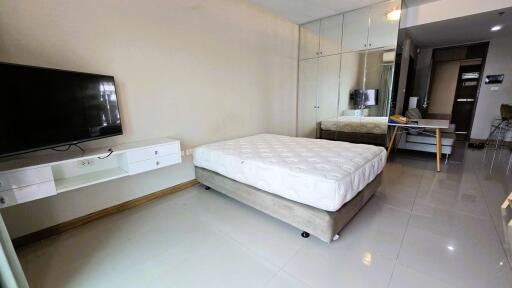 modern bedroom with mirrored closet and mounted TV