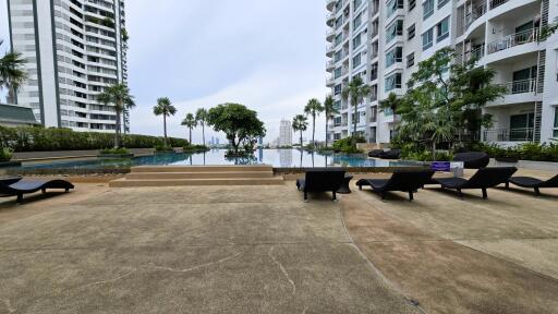 Outdoor pool area with loungers and high-rise buildings