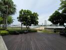 Outdoor patio area with wooden decking and a view of a cityscape including a body of water and trees