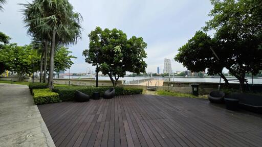 Outdoor patio area with wooden decking and a view of a cityscape including a body of water and trees