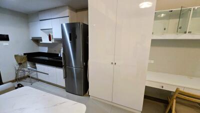 Modern kitchen with white cabinets, stainless steel refrigerator, and black countertops.