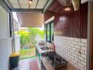 Outdoor covered kitchen with tiled flooring, sink, stove, fan, and garden view