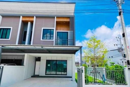 A two-story modern townhouse with a small front yard