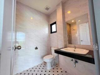 Modern bathroom with tiled walls and flooring, sink, toilet, window, and shower area