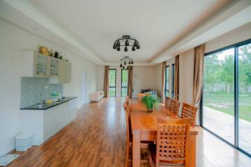 Spacious dining area with wooden table, chairs, and adjacent kitchenette