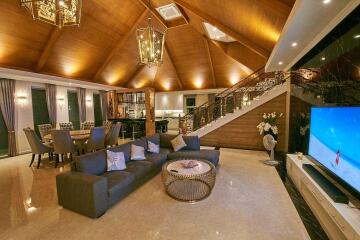 Spacious living room with high wooden ceiling, modern furniture, dining area, and staircase