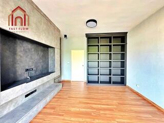 Modern living room with wooden flooring and built-in shelving.