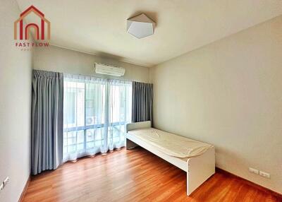 Simple bedroom with wooden floor, single bed, and large window with curtains