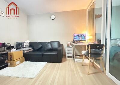 Living room with black sofa, glass door partition, and a small workspace