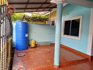 Outdoor area with water storage tank, tiled floor, and window