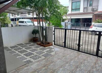 Outdoor courtyard area with tiled flooring, plants, and gated entrance