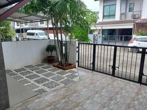 Outdoor courtyard area with tiled flooring, plants, and gated entrance