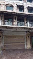 Front view of a multi-story building with a garage door and a balcony