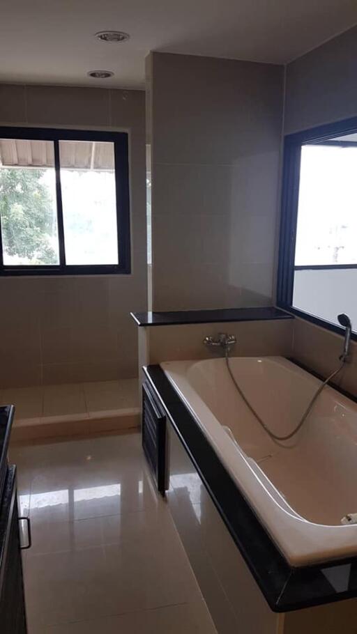 A modern bathroom with a bathtub and large windows.