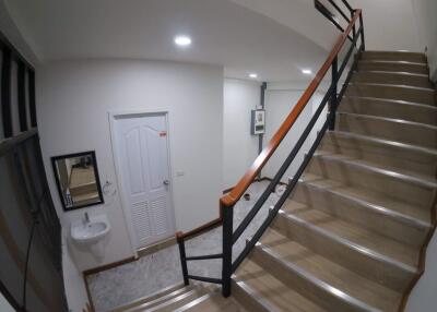 Staircase and landing area with door, sink, and mirror