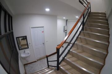 Staircase and landing area with door, sink, and mirror