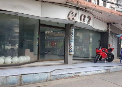 Street view of commercial property with large glass windows and a motorcycle parked outside