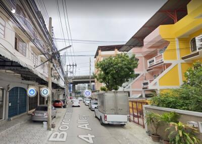 Street view of a residential area with buildings and parked vehicles