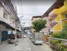 Street view of a residential area with buildings and parked vehicles