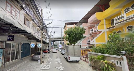 Street view of a residential area with buildings and parked vehicles