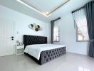 Bright modern bedroom with double bed, two windows with curtains, and wall art