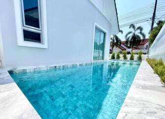 Outdoor swimming pool with clear blue water next to a white building