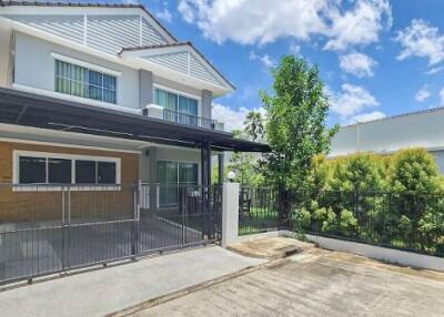 Exterior view of a two-story house with a covered carport and small garden.