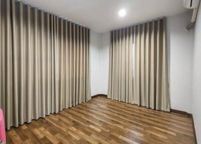 Empty bedroom with wooden flooring and curtains