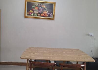 Dining area with wooden table, three chairs, wall clock, and fruit painting