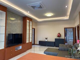 Modern living room with built-in shelving, TV, couch, and decorative elements