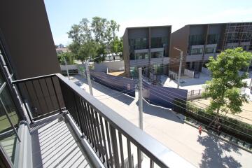 View from apartment balcony overlooking a street and modern buildings