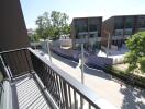 View from apartment balcony overlooking a street and modern buildings