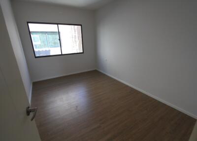 Empty bedroom with wooden flooring and a window