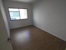 Empty bedroom with wooden flooring and a window