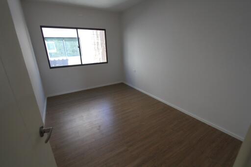 Empty bedroom with wooden flooring and a window