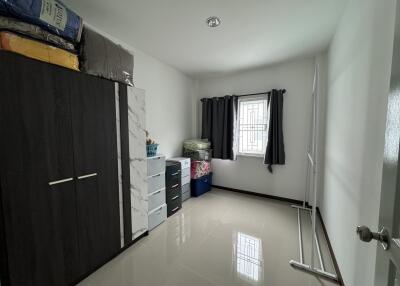 Small bedroom with a window, wardrobe, and storage containers