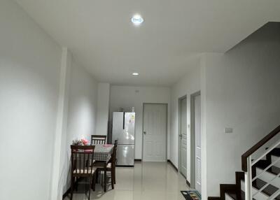 Modern dining space with table and refrigerator near staircase