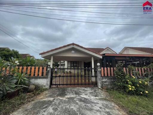 Exterior view of a single-story house with a gated driveway