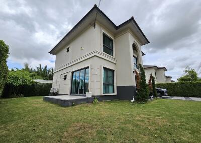 Exterior view of a modern two-story house with large windows and lawn