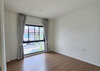 Spacious bedroom with wooden flooring and large window