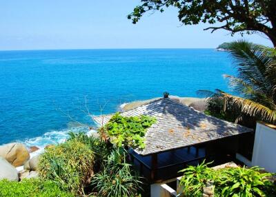 A stunning view of the ocean with a beachfront property surrounded by lush greenery