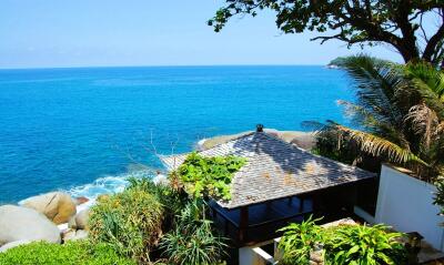 A stunning view of the ocean with a beachfront property surrounded by lush greenery