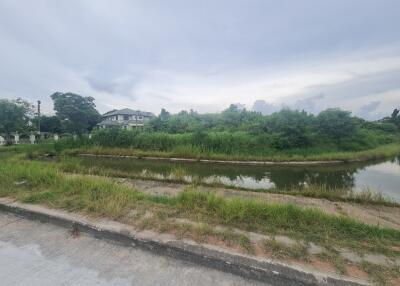 View of grassy area and pond with house in the background